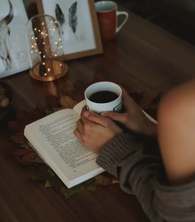 Femme tenant un café en lisant